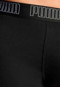 Zwarte, fitting boxershorts met een brede elastische tailleband waarop "PUMA" in het wit is gedrukt. Soepele textuur en geen zichtbare patronen.
