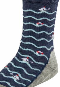Marinefarbene Socken mit einem Wellenmuster in Hellblau und roten Akzenten, verziert mit kleinen Segelbootmotiven und einer grauen verstärkten Ferse.
