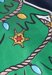 Žalia medžiaga su Kalėdų medžio dizainu, kuriame yra žvaigždė su raudonu centru, dekoratyvinės mėlynos ir geltonos spalvos lemputės bei virvės akcentas.