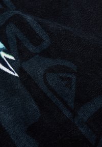 Tecido de fleece preto com padrões gráficos em azul e branco, apresentando uma textura suave e um brilho sutil. Ideal para calor e conforto.