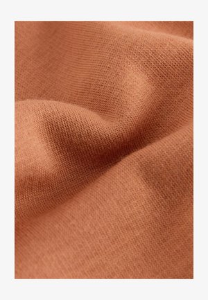 Tela de color óxido con una textura suave, que presenta un patrón de punto fino y variaciones sutiles en el tono. Apariencia suave y ligera.