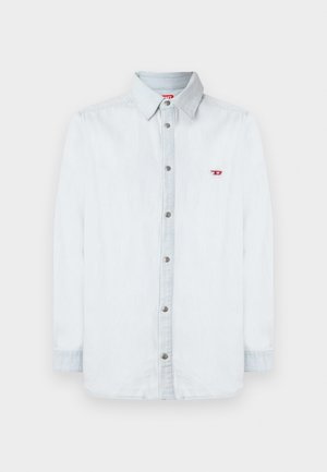 Camisa de mezclilla azul claro con un frente abotonado, mangas largas y un pequeño logo rojo en el lado izquierdo del pecho. Los botones plateados completan el diseño.