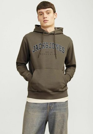 Brun hoodie med framficka, dragsko i huvan och textlogotypen "JACK&JONES". Bärs över en ljusklädd skjorta och matchas med blå jeans.