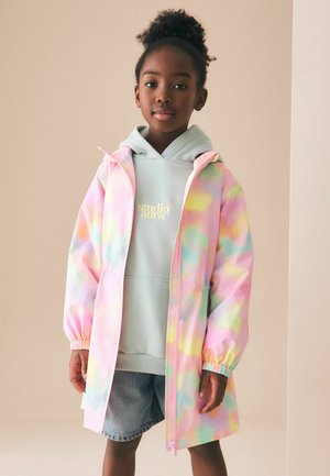 Leichte Regenjacke in Pastell-Tie-Dye mit verstellbarer Kapuze und elastischen Bündchen, kombiniert mit einem mintgrünen Hoodie und Jeansshorts.