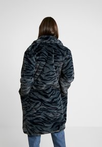 Manteau en fausse fourrure gris foncé avec motif à rayures de tigre, doté d'un col haut, d'une texture douce et de grandes poches latérales.