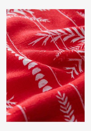 Red fabric with a textured surface featuring white botanical patterns and line accents, creating a visually striking contrast.