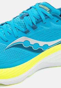Chaussure de course légère en maille bleu vif avec des accents argentés. Dotée d'une semelle jaune rembourrée et d'un dessus texturé pour la respirabilité.