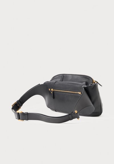 Μαύρη δερμάτινη τσάντα χιαστί με ρυθμιζόμενο λουράκι, μπροστινή τσέπη με φερμουάρ και χρυσούς μεταλλικούς λεπτομέρειες σε λευκό φόντο.