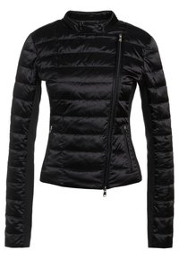 Veste matelassée noire avec fermeture éclair asymétrique à l'avant, deux poches latérales zippées, col haut et panneaux en tissu contrastant sur les manches.
