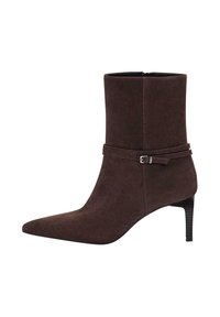Stivale alla caviglia in suede marrone con punta affusolata e tacco alto sottile. Presenta una cintura avvolgente con dettaglio di fibbia metallica. Texture liscia.