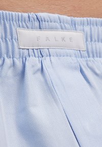 Blauw visgraatpatroon stof met een zachte textuur, voorzien van een elastische tailleband en een wit label met het reliëf "FALKE".
