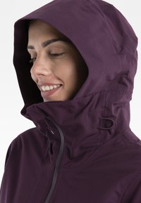 Fioletowa kurtka z kapturem i wysokim kołnierzem, z zamkiem błyskawicznym i teksturowanym materiałem. Hoodie zaprojektowano z myślą o ciepłe i komforcie.