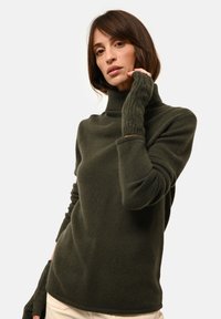 Ciemnozielony sweter golfowy z miękkiego materiału, z prążkowanymi akcentami na kołnierzu i rękawach, co dodaje tekstury.