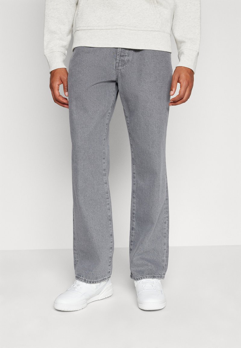 Gray denim trousers with a loose fit, straight legs, and subtle fading. Paired with white sneakers, creating a casual look.