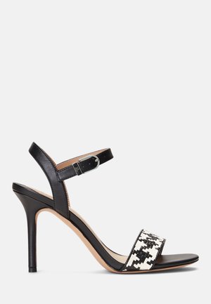 Sandale à talon haut noire avec bride de cheville et bouclerie argentée, la bride avant présente un détail en motif tissé noir et blanc.