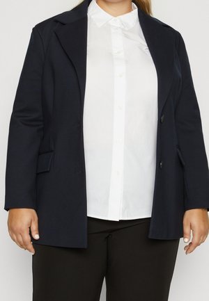 Marineblauer Blazer mit strukturiertem Design, ausgestattet mit einem Revers mit Kerbe, zwei vorderen Knöpfen und Seitentaschen, kombiniert mit einem weißen Hemd.
