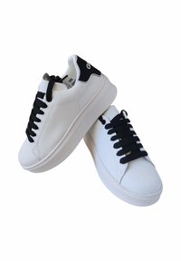 Sneakers bianchi con lacci neri e accentuazione nera sul tallone. Realizzati in materiale liscio, presentano una punta arrotondata e un design minimalista.
