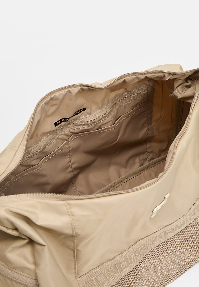 Bolso beige con una sección de malla texturizada en la parte inferior. El interior cuenta con múltiples bolsillos y un forro de tela suave, con cierre de cremallera.