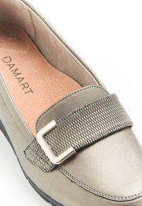 Metalen grijze loafer met synthetisch bovenwerk, opvallende geweven band en gepolijste sluitingdetails. Gevoerde binnenzool, platte rubberen zool en stikselaccenten.