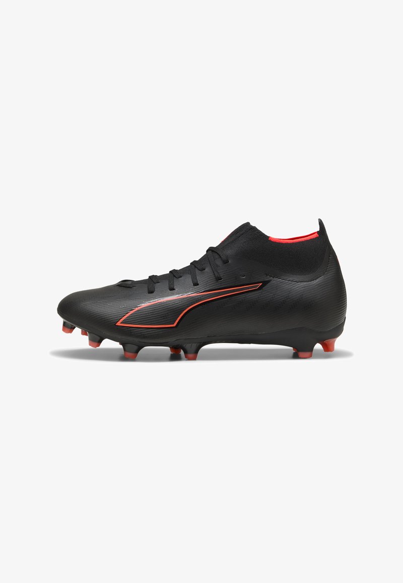 Chaussure de football noire avec des accents rouges, design de chaussette haute à la cheville, crampons moulés et lacets, vue du côté extérieur sur fond blanc.