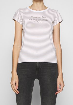 Kobieta ubrana w jasnoróżowy i biały pasiasty t-shirt z krótkim rękawem z napisem "Abercrombie & Fitch Est. 1892 New York" i czarne jeansy.
