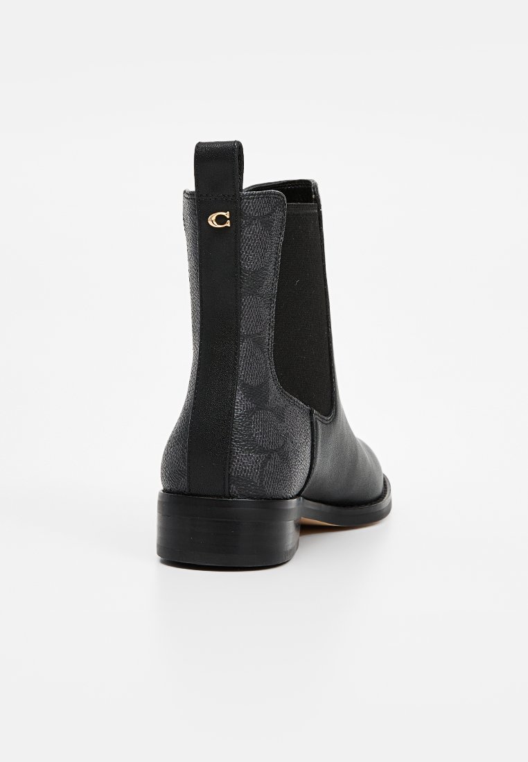 Bottines noires avec un devant en cuir et un dos en tissu à motif. Elles sont dotées de panneaux latéraux élastiques, d'un petit talon et d'un détail logo doré.