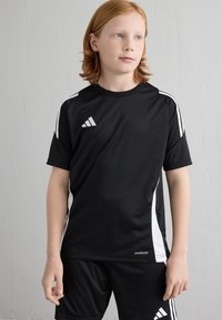 Čierne atletické tričko s bielymi detailmi a tromi pruhmi. Vyrobené z ľahkého materiálu, s logom značky a označením Aeroready.