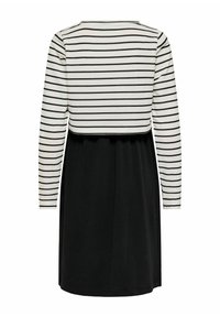 Vestido negro con un crop top de manga larga blanca que presenta rayas negras horizontales, visto desde la parte de atrás.