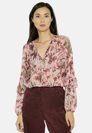 Floral blouse in soft pink fabric with a v-neck and button front. Features long puff sleeves and a delicate floral pattern in burgundy and green.