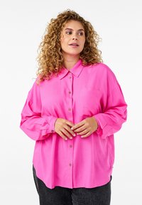 Ružičasta košulja s kragnom, dugim rukavima, dugmadi sprijeda i džepom na prsima. Ima opušteni kroj i glatku teksturu.