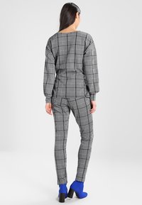 Szary i czarny wzorzyste ubranie składające się z luźnej bluzki i dopasowanych spodni, w połączeniu z niebieskimi botkami do kostek. Miękka tekstura, casualowy styl.