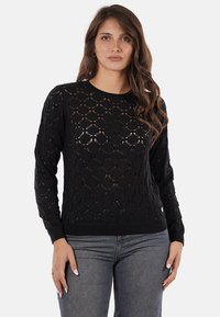 Maglione nero lavorato a maglia con un motivo a diamante aperto, maniche lunghe e orlo a costine. Realizzato in filato leggero con una finitura testurizzata.