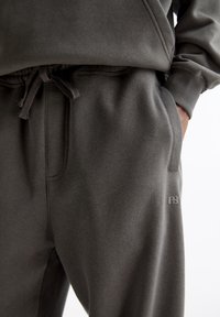 Grijze katoenen sweatpants met een zachte textuur, elastische tailleband en zichtbare koord. Bevat een zijzak en een logo op de dij.