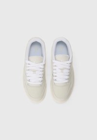 Beige sneakers med hvite snører, glatt tekstur, gummisåler og et lyseblått innersåle med en liten logo på tungen.
