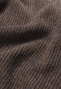 Teksturowana dzianina w odcieniach brązu i ciemnego niebieskiego, charakteryzująca się prążkowanym wzorem z widocznymi szwami i miękkim wyglądem.