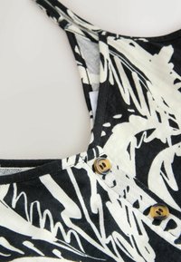 Schwarz-weißer gemusterter Stoff mit strukturiertem Finish; verfügt über einen U-Boot-Ausschnitt und zwei braune Knöpfe an der Schulternaht.