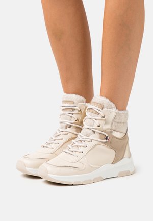 Baskets montantes beiges avec col en fausse fourrure, lacées à l'avant, en cuir lisse et matériaux textiles, avec une cheville rembourrée et une semelle texturée.