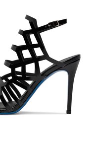 Sandalo nero con tacco alto, design a ritagli geometrici, finitura lucida e un accento blu sulla suola. Include una cinghia per caviglia regolabile.