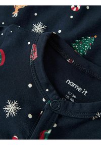 Navyblaue Baumwoll-Einteiler mit festlichen Mustern, darunter Weihnachtsbäume, Schneeflocken und Zuckerstangen. Druckknopfverschluss am Ausschnitt.