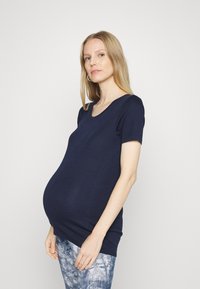 T-shirt de maternidade azul marinho, de mangas curtas, com decote redondo. Tecido suave e elástico projetado para conforto, com um corte solto em torno da barriga.