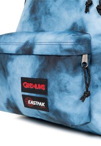 Zaino tie-dye blu con patch logo "Gremlins" ed "Eastpak", con coulisse regolabile e dettagli con cerniera sulla tasca frontale.