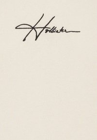 Tessuto bianco con una firma in corsivo nera che dice "Hollister." La texture è liscia e leggermente elasticizzata.