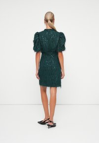 Teal sequin dress with textured, fluffy fabric, puff sleeves, and a fitted silhouette, featuring a mid-thigh length and fringe hem.
