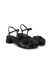 Sandali in pelle nera con tacco a blocco, caratterizzati da grandi decorazioni a forma di fiore sulla punta e sottili cinturini alla caviglia regolabili.