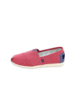 Zapato casual sin cordones con parte superior de lona roja, lengüeta azul en el talón, suela color beige y una pequeña etiqueta negra con logo en el lateral.