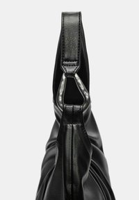 Zwarte leren handtasriem bevestigd aan een zilveren driehoekige metalen ring, met nadruk op textuur en stikdetails op een effen achtergrond.