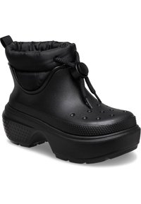 Botas de tobillo impermeables negras con un collar acolchado, cierre de cordón, perforaciones para transpirabilidad y una suela gruesa tipo plataforma.