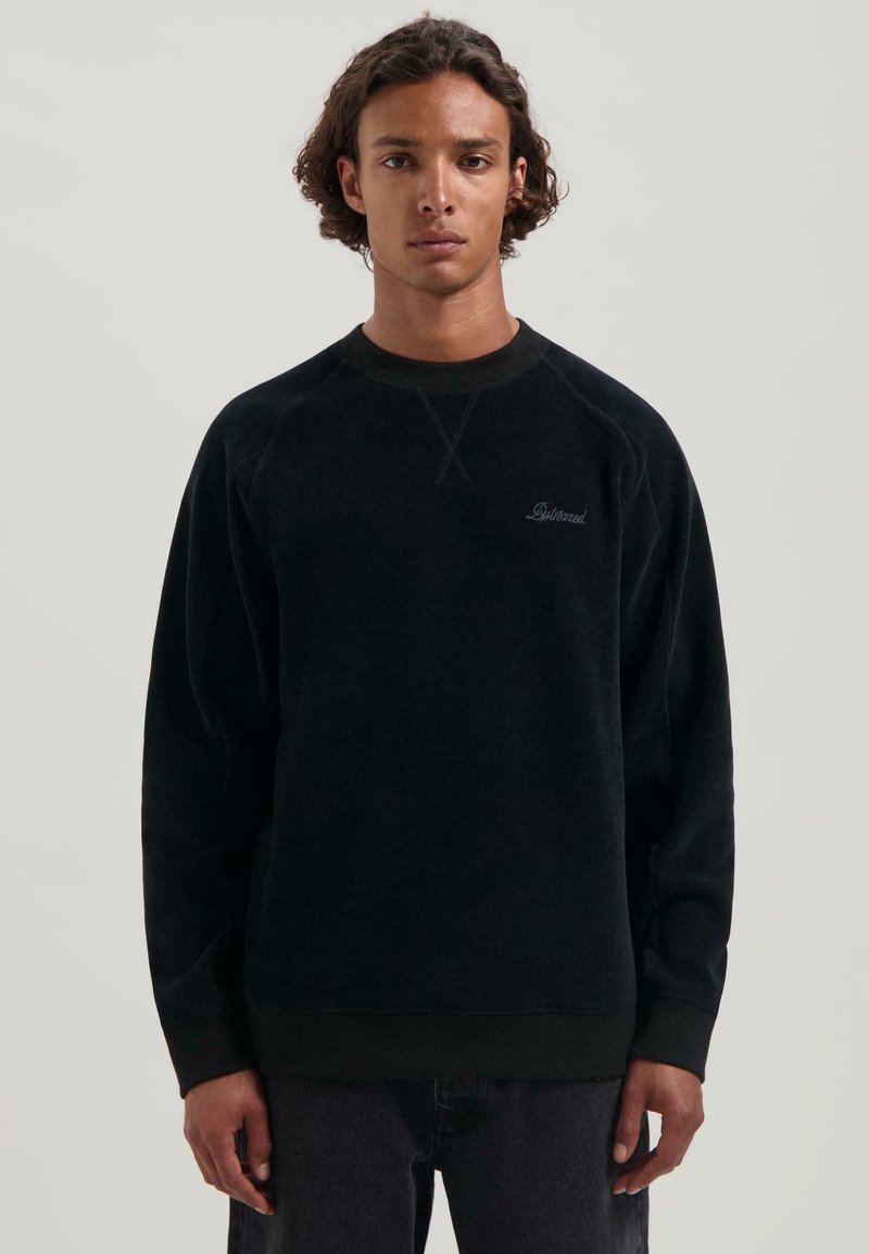 Sudadera de forro polar negra con mangas raglán, puños y dobladillo de canalé. Presenta un sutil bordado de logo en el pecho y una textura suave.