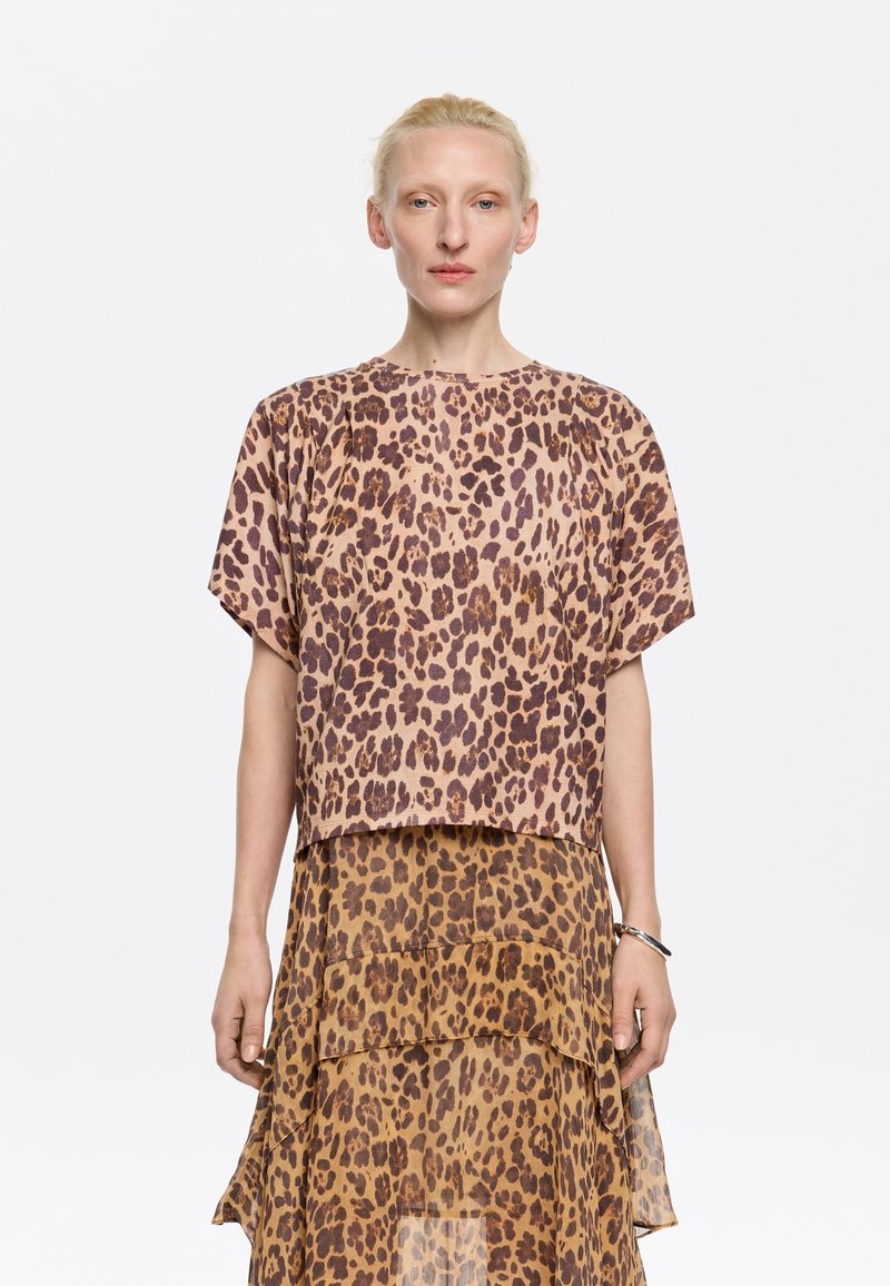 Leopard-print top in light tan and brown, loose fit with short sleeves. Paired with matching tiered skirt, featuring similar pattern and sheer texture.