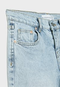 Un gros plan sur un jean en denim bleu clair montrant la poche avant, la petite poche à monnaie, les passants de ceinture, les rivets en métal et l'étiquette de taille "Stradivarius 34".